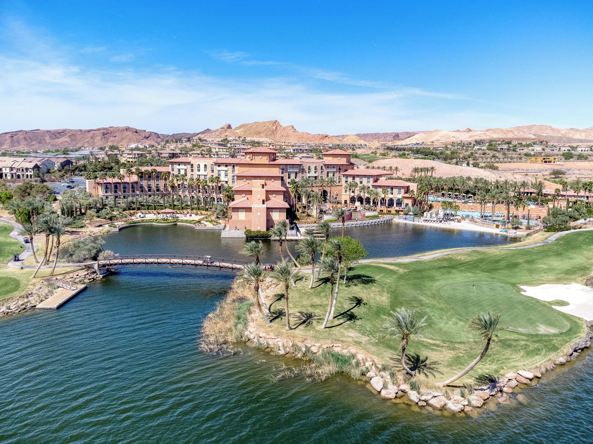 A resort with a central water feature, a golf course, and a desert landscape in the background.