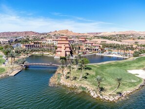 Ein Resort mit einem zentralen Wasserspiel, einem Golfplatz und einer Wüstenlandschaft im Hintergrund.