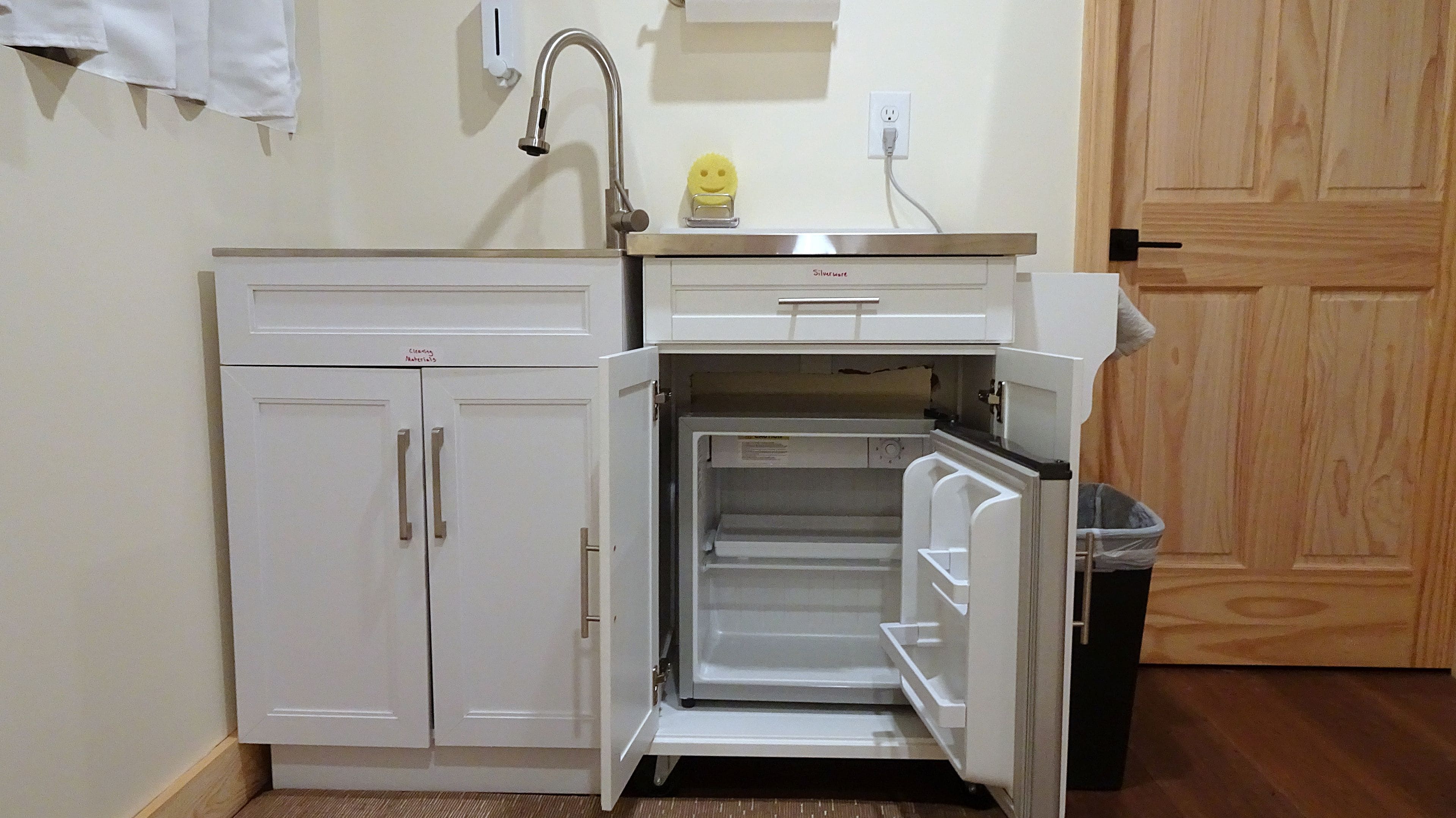 Une cuisine compacte dotée d’un réfrigérateur encastré, d’un évier et d’un petit plan de travail.