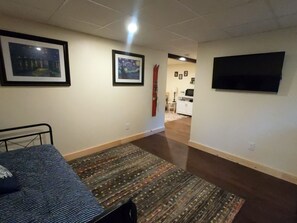 A room with a bed, a television mounted on the wall, and a door leading to another room. - Quiet Property w/ Private Entrance (Weare)