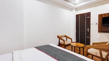 A hotel room with a bed, a desk, a chair, and a wardrobe.