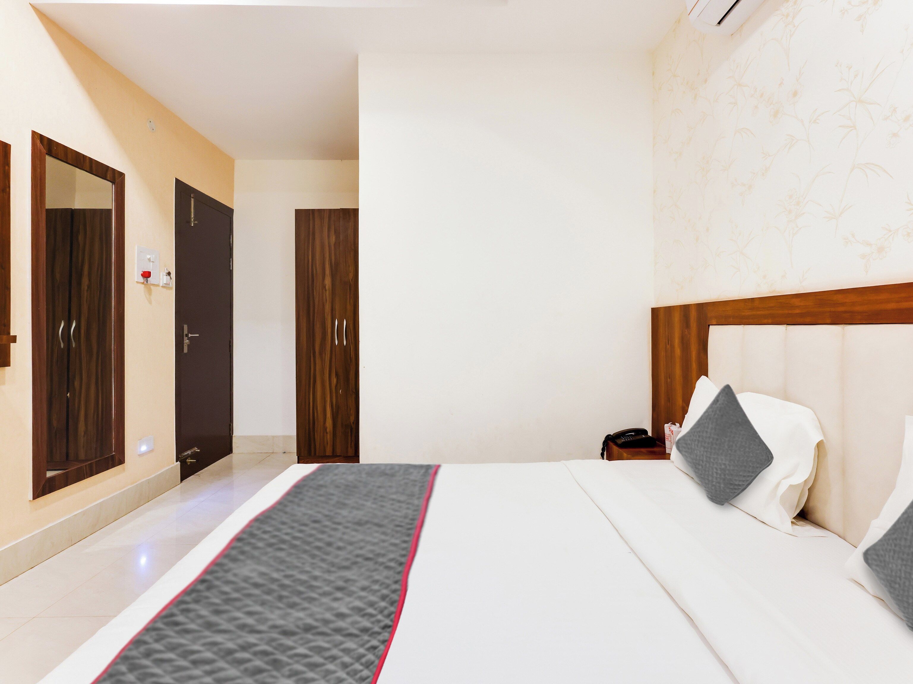 A hotel room with a bed, bedside table, and a wardrobe.