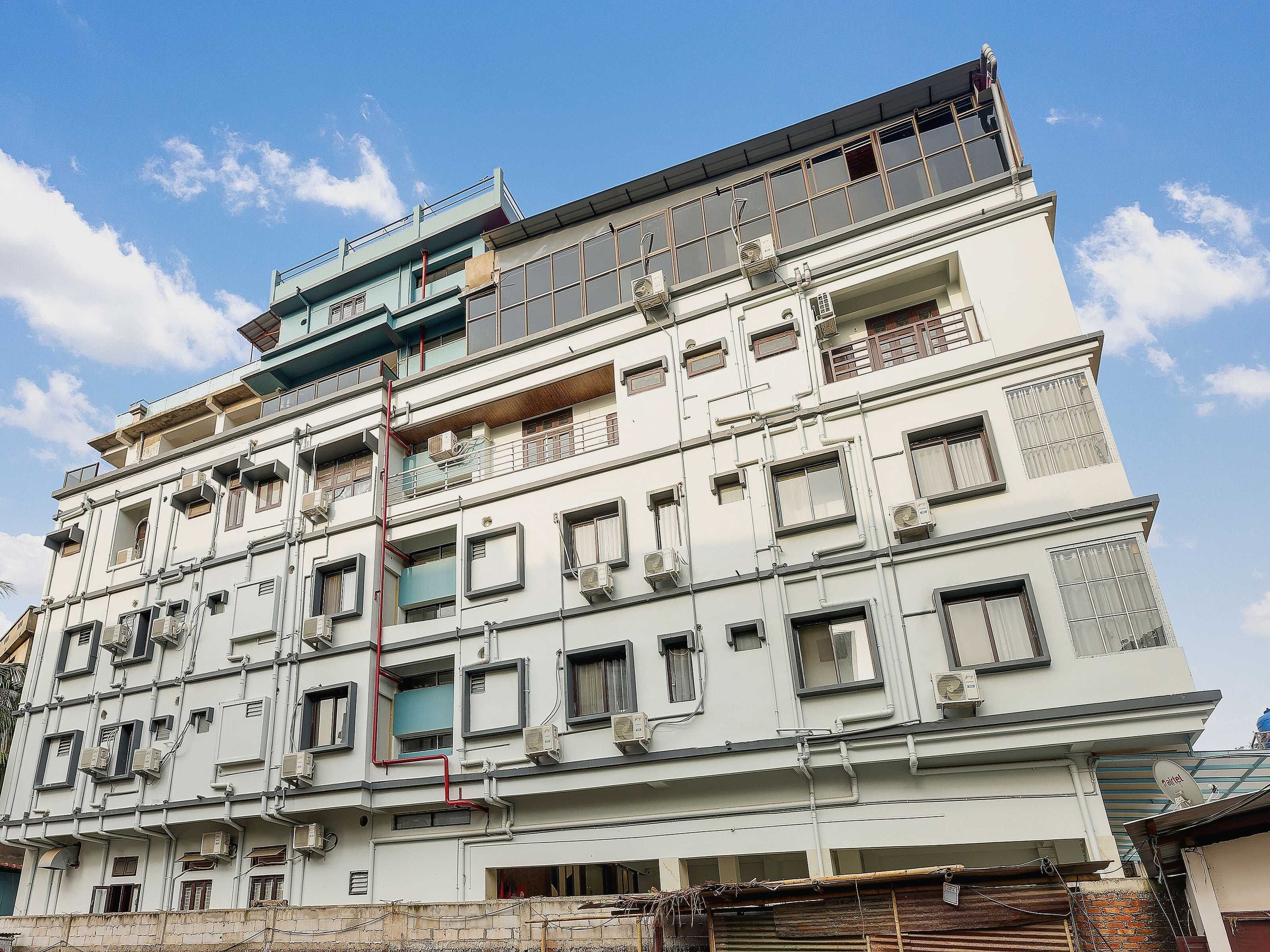 Un edificio de varios pisos con numerosas ventanas y balcones, algunos con barandillas.