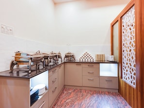 A kitchen with a marble countertop, stainless steel appliances, and a decorative partition. - Townhouse Royal Inn (Guwahati)
