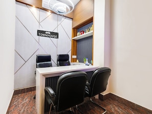 A conference room with a white table, black leather chairs, a sign reading 'OYO TOWNHOUSE', and a shelf with decorative items. - Townhouse Royal Inn (Guwahati)