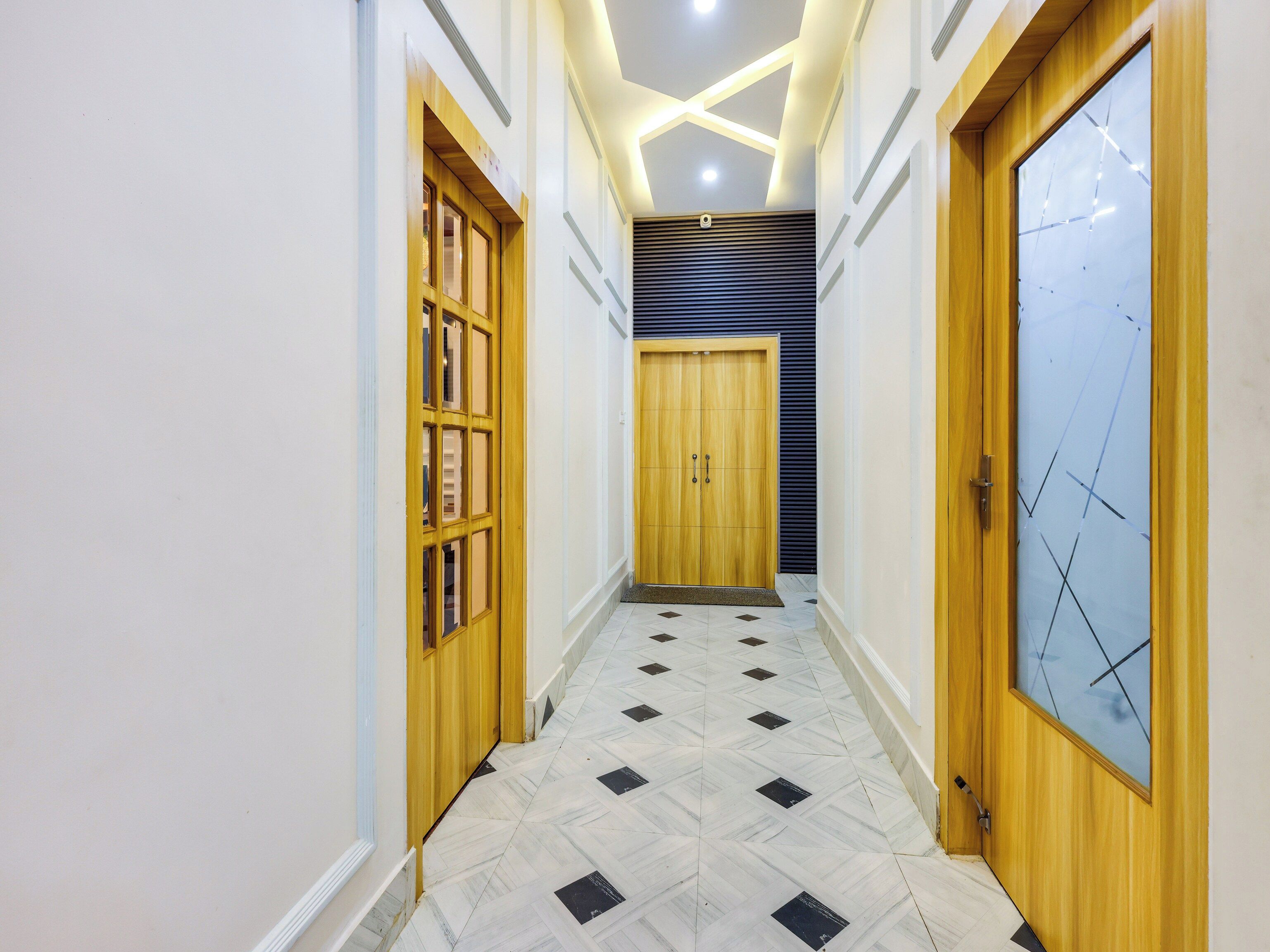 A hallway with a wooden door, a glass door, and a tiled floor.