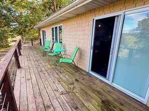 A wooden deck with outdoor seating and a sliding glass door. - Cozy 2-bedroom cabin in beautiful Mammoth Spring (Mammoth Spring)