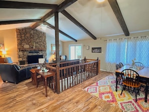 A cozy living room with a stone fireplace, wooden furniture, and a balcony with a railing. - Cozy 2-bedroom cabin in beautiful Mammoth Spring (Mammoth Spring)