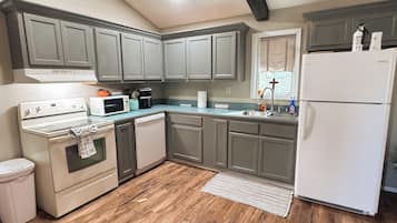 A kitchen with grey cabinets, a white stove, and a white refrigerator.