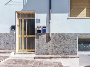 A building facade with a wooden door, mailboxes, and a window. - Casa Lara (Carloforte)