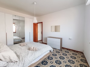A bedroom with a bed, a wardrobe, a bedside table, and a mirror. - Casa Lara (Carloforte)