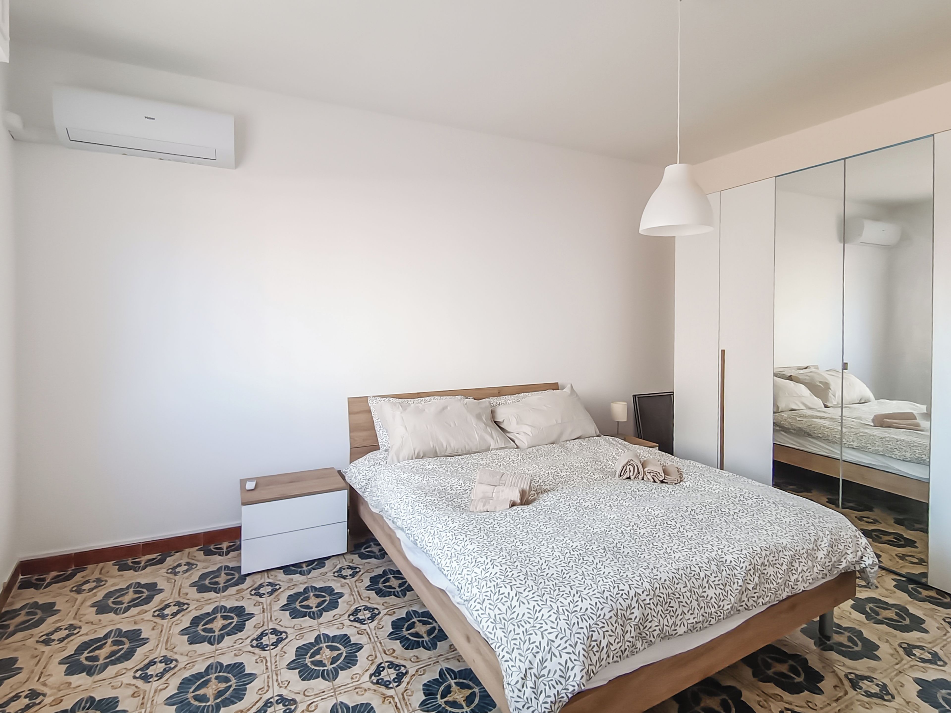 A bedroom with a bed, bedside table, and a mirror.