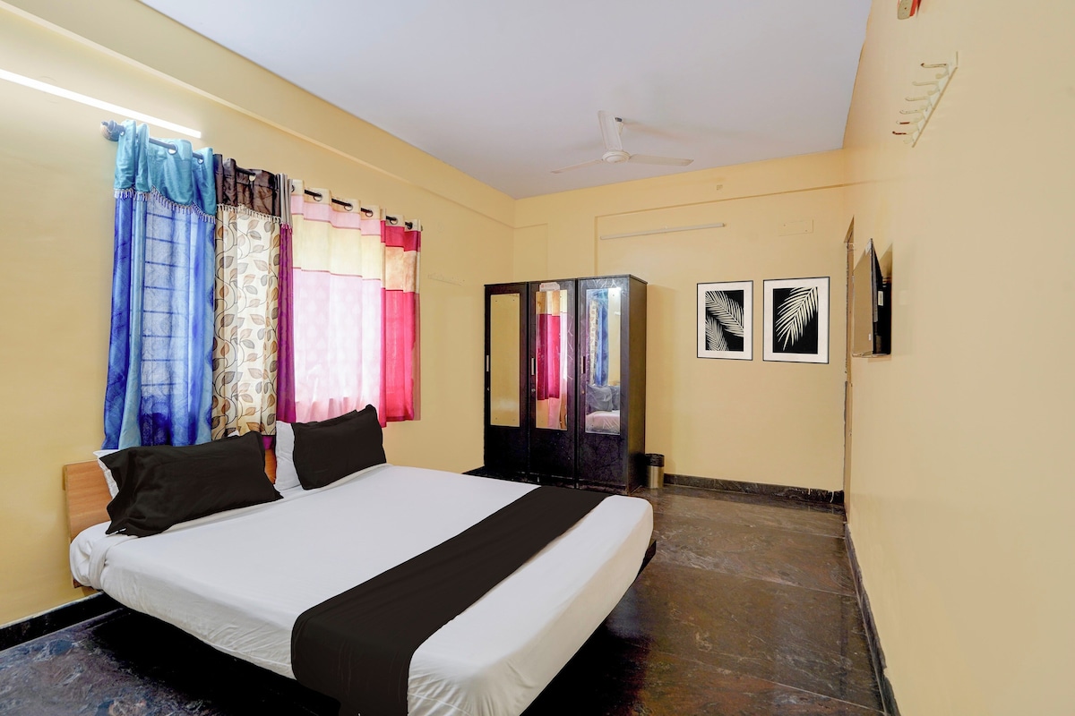 Una habitación de hotel con cama, cortinas, un armario y dos cuadros en la pared.