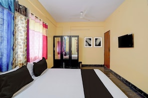 Una habitación de hotel con cama, cortinas, ventilador de techo y una puerta.