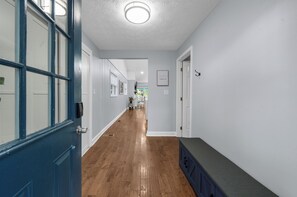 A hallway with wooden flooring, white walls, and a blue door.
