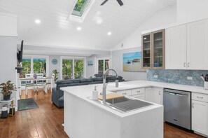 A modern kitchen with white cabinetry, a built-in dishwasher, and a large island with a sink.