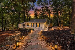 A house with a porch, surrounded by trees and a stone pathway.