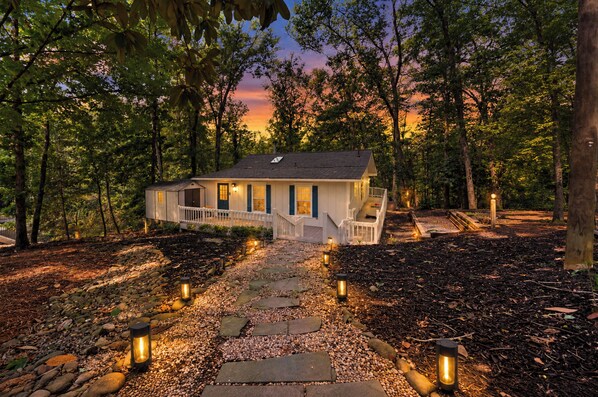 A house with a porch, surrounded by trees and a stone pathway.