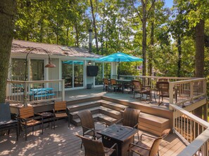 A deck with outdoor seating, a covered area, and a view of the surrounding trees.