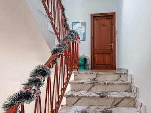 A staircase with a wooden handrail and a red railing, leading to a wooden door. - Casa Lara - Charming Apartment in the Heart of Carloforte's Historic Center (Carloforte)