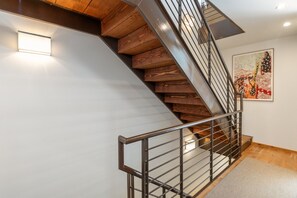 A modern staircase with wooden steps and metal railings, leading to a landing with a light fixture. - The Fairlee at Owl Meadows - Elegant 3BR + Mountain Views (Telluride)