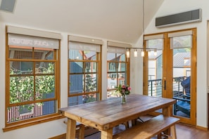 A dining area with a wooden table and benches, large windows with blinds, and a view of the outside. - The Fairlee at Owl Meadows - Elegant 3BR + Mountain Views (Telluride)