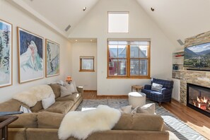 Ein geräumiges Wohnzimmer mit hoher Decke, Kamin und großen Fenstern.
