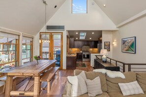 A spacious living area with a wooden dining table, a sofa, and a view of the outside.