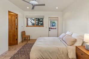 A bedroom with a bed, a chair, a wooden door, a window with a view, and a ceiling fan. - The Fairlee at Owl Meadows - Elegant 3BR + Mountain Views (Telluride)