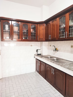 A kitchen with wooden cabinets, a marble countertop, and a stainless steel sink. - Traditional, family-friendly apartment in the heart of Tangier (Tanger)
