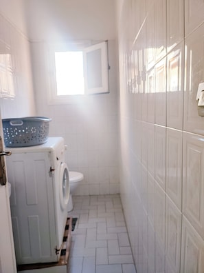 A narrow laundry room with a washing machine, a dryer, and a small window. - Traditional, family-friendly apartment in the heart of Tangier (Tanger)