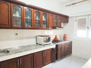 Una cucina con mobili in legno, forno a incasso e una finestra con persiane.