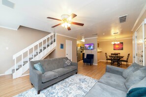 A living room with a grey sofa, a blue patterned rug, a ceiling fan, and a TV mounted on the wall. - Urban Oasis: In the Medical Center (San Antonio)