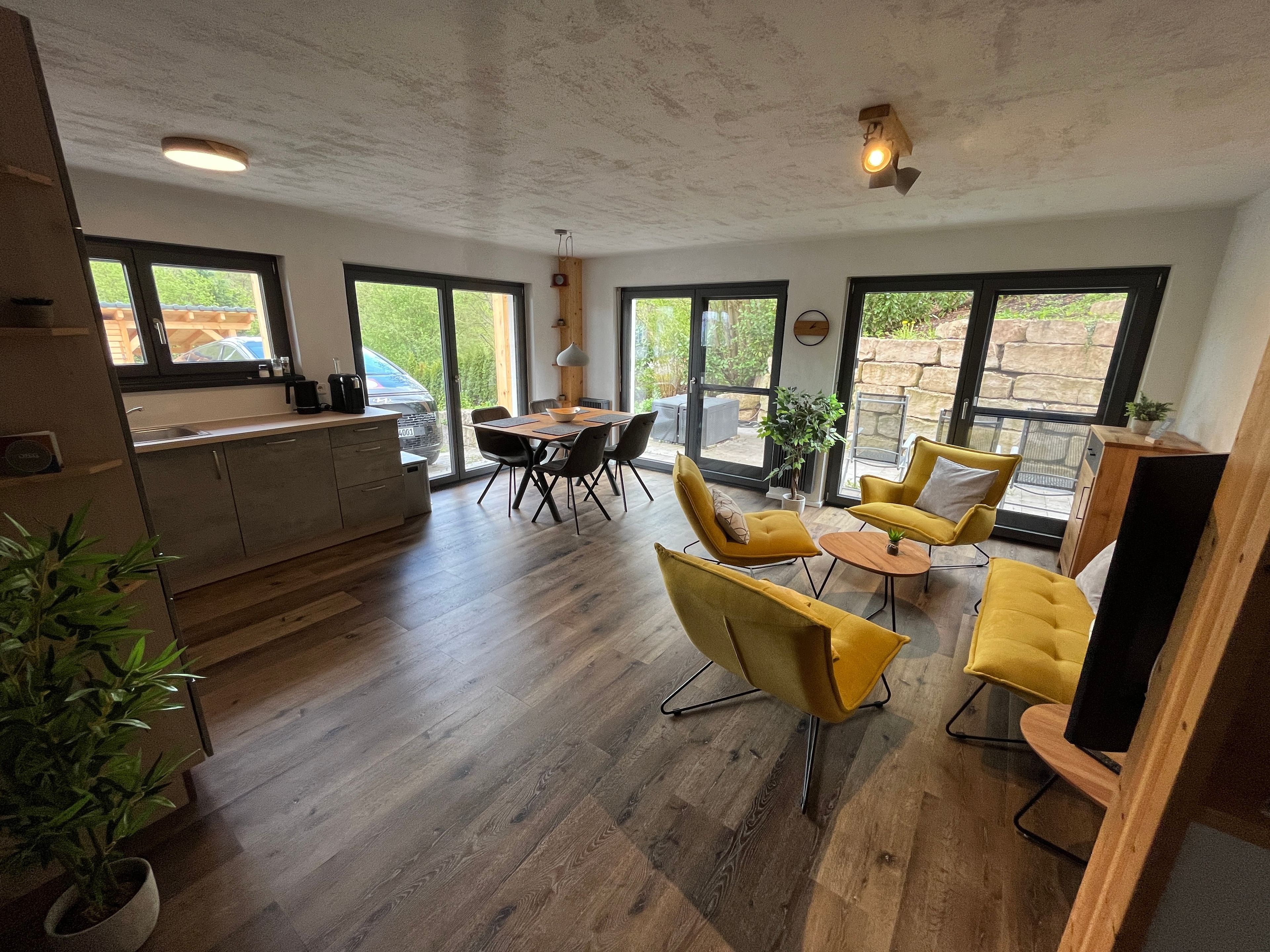 A modern kitchen with a dining area, large windows, and a view of the outdoors.