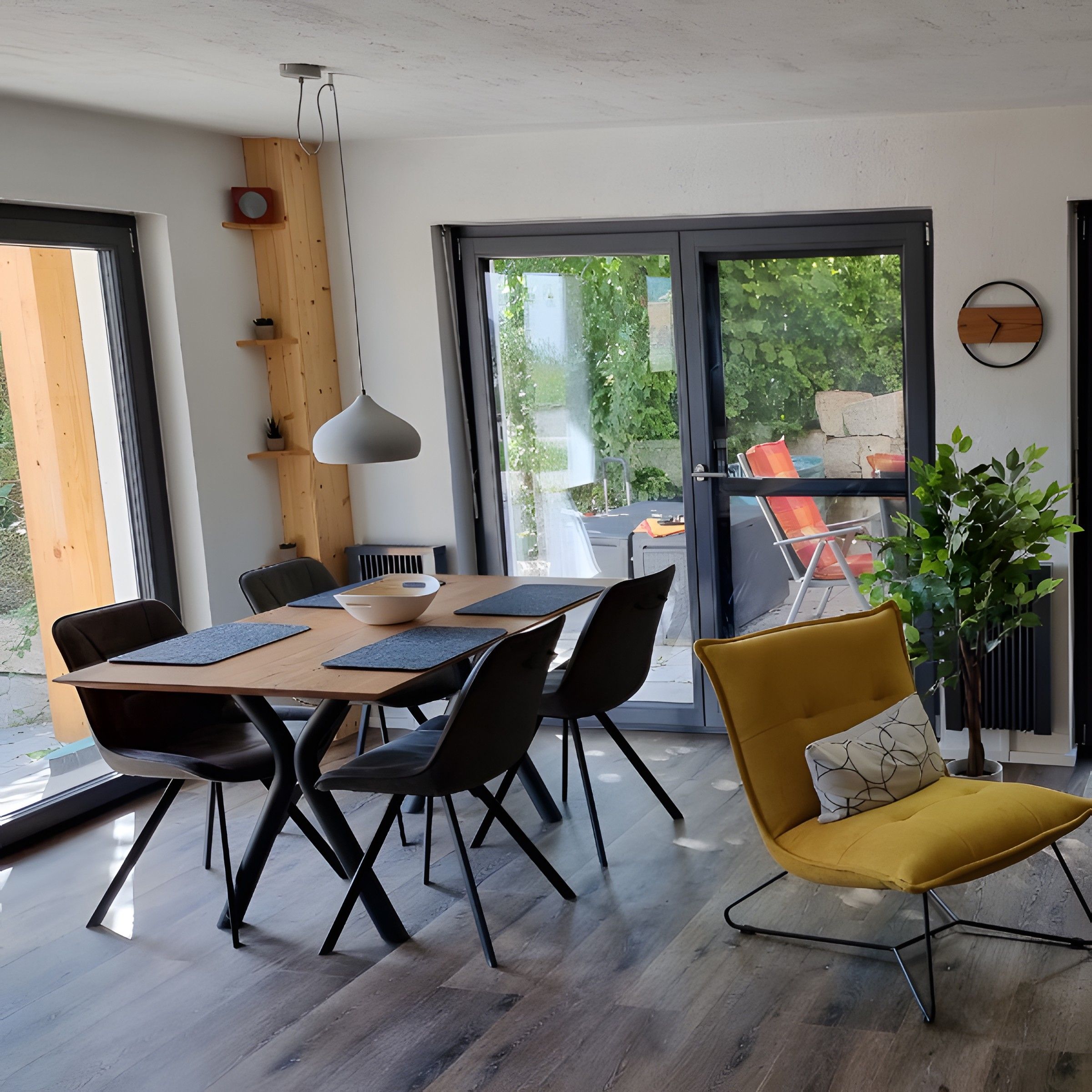 A modern dining area with a wooden table, black chairs, and a yellow armchair.