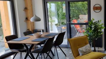 A modern dining area with a wooden table, black chairs, and a yellow armchair.