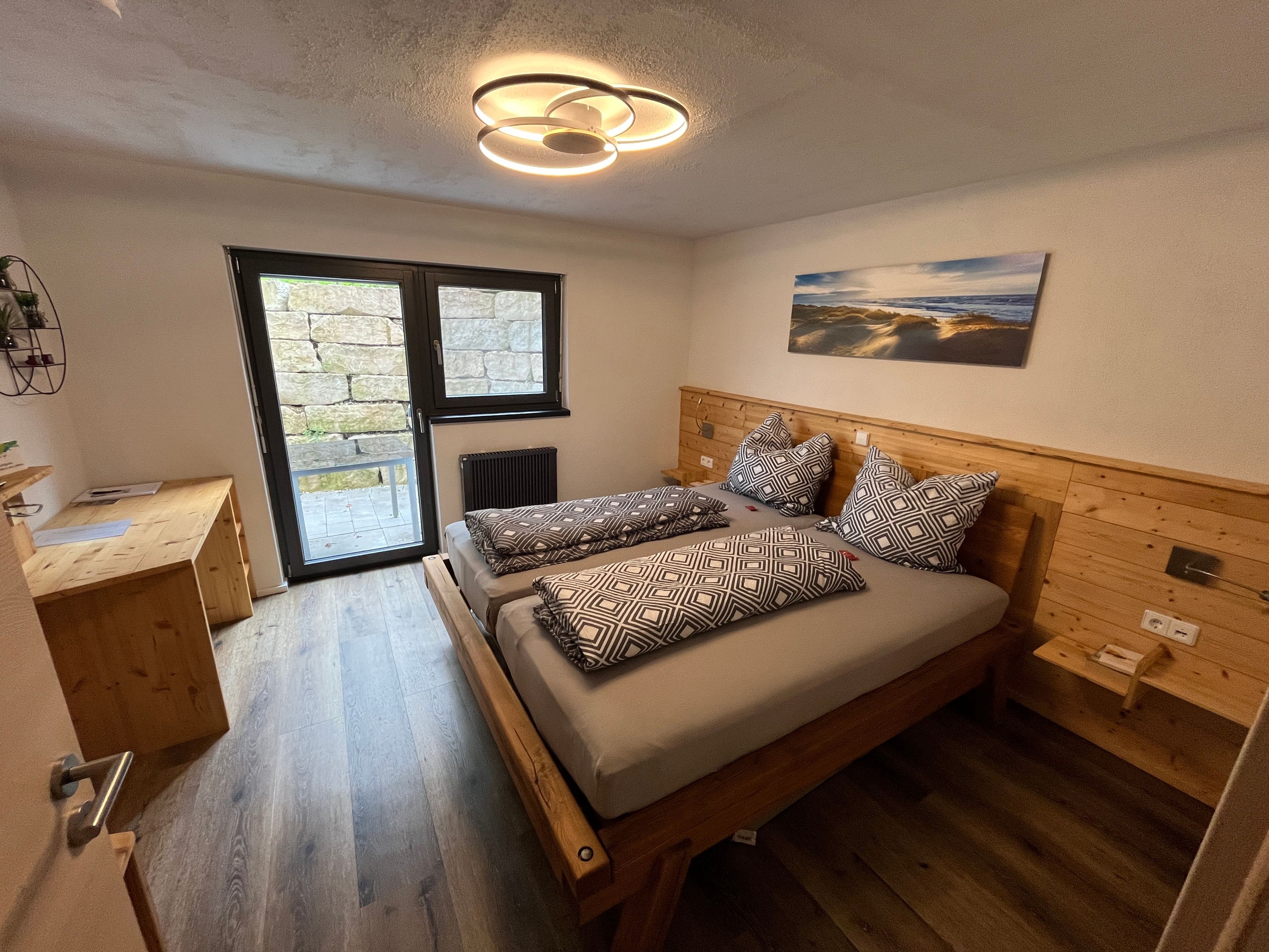 Ein Schlafzimmer mit einem Doppelbett, einem hölzernen Kopfteil, einem Nachttisch, einer Heizung und einem Fenster mit Blick.