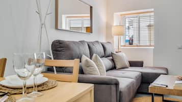 Una sala de estar con un sofá, una mesa de comedor con un mantel individual y una lámpara.