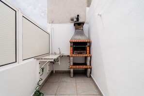 A compact outdoor kitchen area with a built-in pizza oven, a small countertop, and a sink. - Casa Sol e Sal  3-Min Walk to Beach & Old Town (Albufeira)