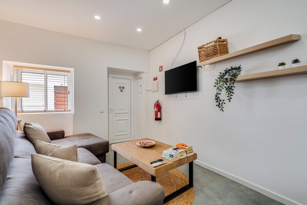 A modern living room with a sofa, a coffee table, a TV, and a fire extinguisher. - Casa Sol e Sal  3-Min Walk to Beach & Old Town (Albufeira)