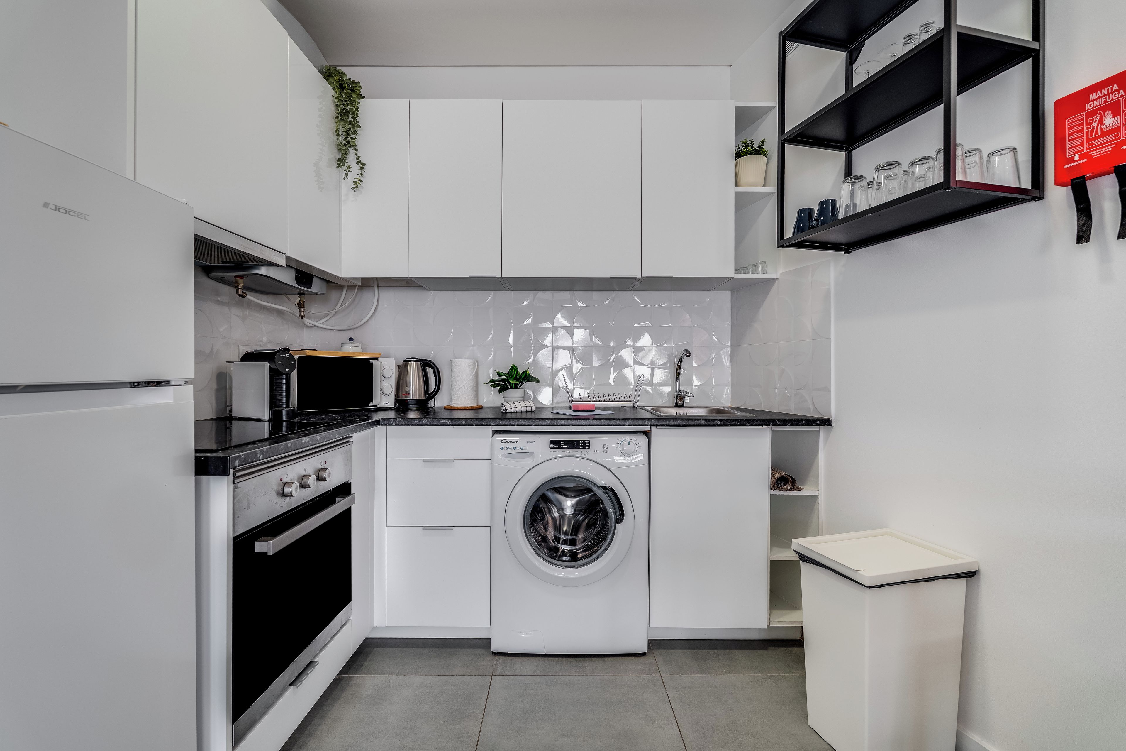 Une cuisine moderne avec des meubles blancs, un lave-linge, un four à micro-ondes et un évier.