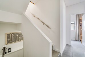 A staircase with a handrail, a wall-mounted decorative panel, and a door leading to another room. - Casa Sol e Sal  3-Min Walk to Beach & Old Town (Albufeira)