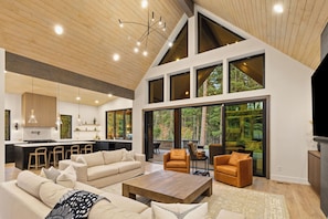 A spacious living area with a high ceiling, large windows, and a modern kitchen. - Lux 6 BdRm, Media Rm, Built-in BBQ, Chefs Kitch (Cle Elum)