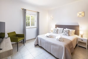 A hotel room with a bed, a chair, a desk, and a window with curtains. - New! Quinta Lamy - Villa with Pool near Carvoeiro (Lagoa)