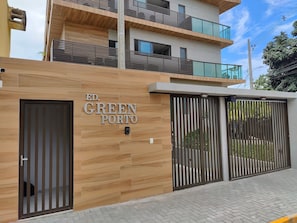 A modern building with a wooden facade, a nameplate reading "ED. GREEN PORTO", and a gated entrance. - Green P. Ap. 307 Leo Milán (Ipojuca)
