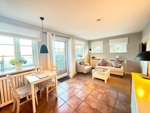 A well-lit living room with a dining area, a sofa, and a TV. - Deichhof - Apt. 18 (Dunsum)