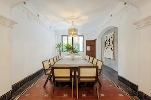 A dining room with a long table, chairs, a chandelier, and a vase with plants. - Timeless Charm in Condesa 6BR, Perfect Terrace (Mexico City)