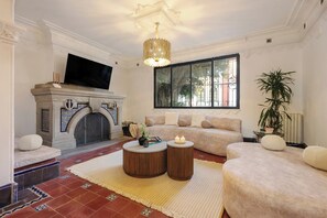 A living room with a fireplace, a television, a sofa, and a large window. - Timeless Charm in Condesa 6BR, Perfect Terrace (Mexico City)