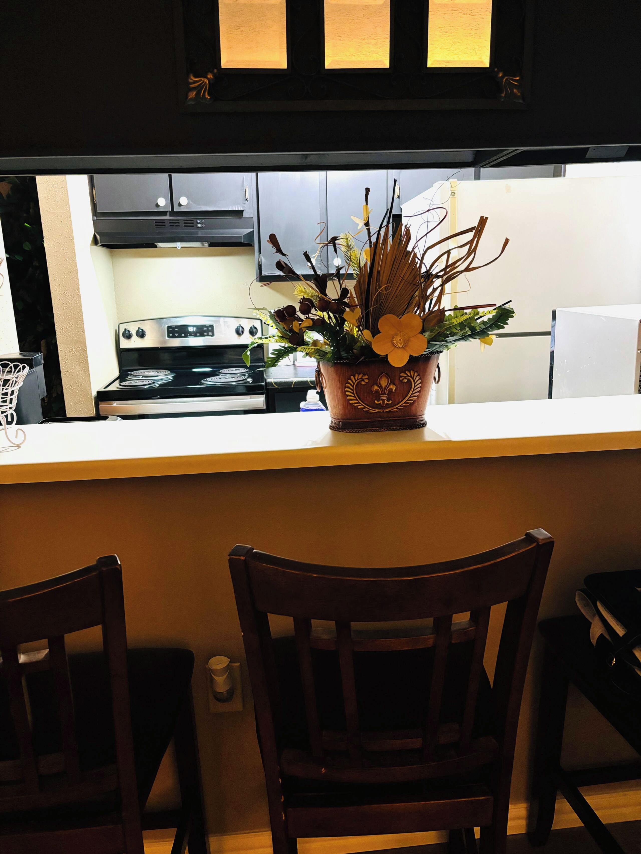 Una cocina con estufa, armarios y un florero sobre la encimera.