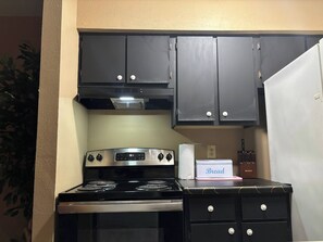A kitchen with a stove, oven, and dark cabinets.